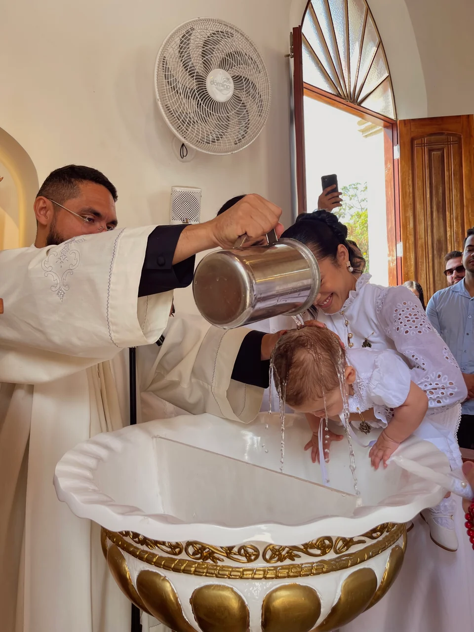 Criança recebe a água do batismo em celebração registrada pela VS Movie.